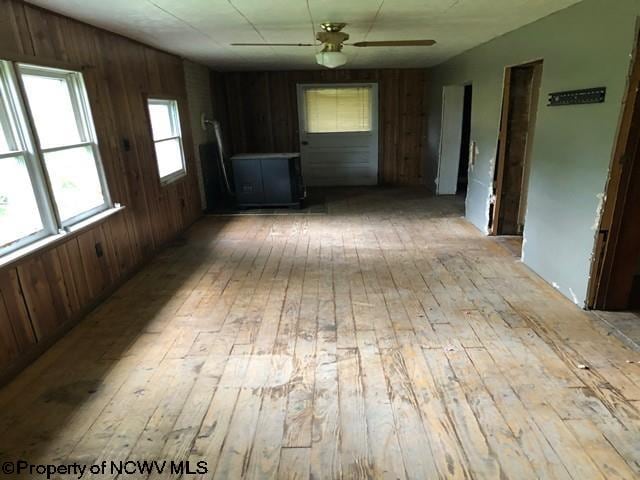 unfurnished room featuring wood walls, ceiling fan, and light hardwood / wood-style floors