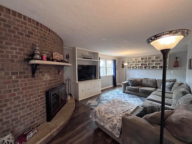 living room featuring a textured ceiling, dark hardwood / wood-style floors, and a brick fireplace