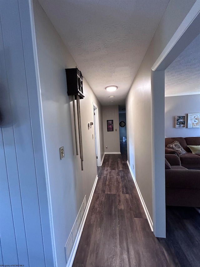 hallway with a textured ceiling and dark hardwood / wood-style floors