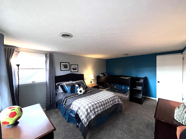 bedroom with a textured ceiling and dark colored carpet