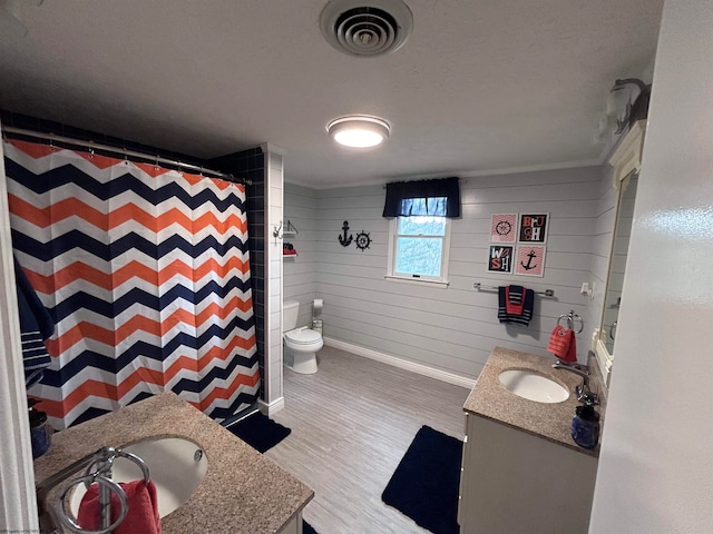 bathroom with vanity, hardwood / wood-style flooring, toilet, curtained shower, and wood walls