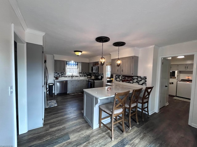 kitchen featuring a kitchen bar, appliances with stainless steel finishes, decorative backsplash, and dark wood-type flooring