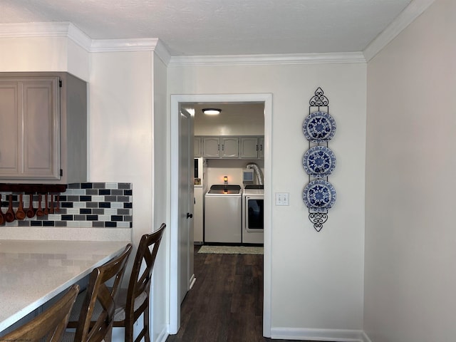 kitchen featuring dark hardwood / wood-style floors, crown molding, gray cabinets, decorative backsplash, and washer and clothes dryer