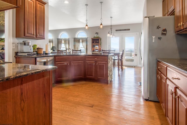 kitchen with pendant lighting, vaulted ceiling, stainless steel appliances, and light hardwood / wood-style flooring