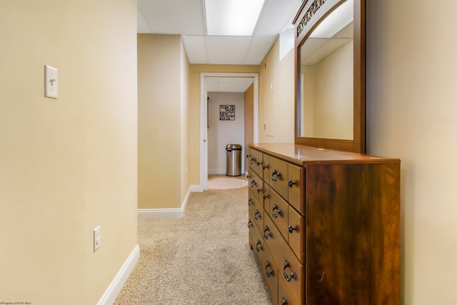 hallway with a paneled ceiling and light carpet