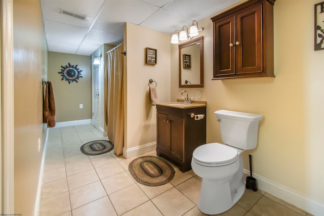 bathroom featuring toilet, vanity, tile patterned floors, and a paneled ceiling