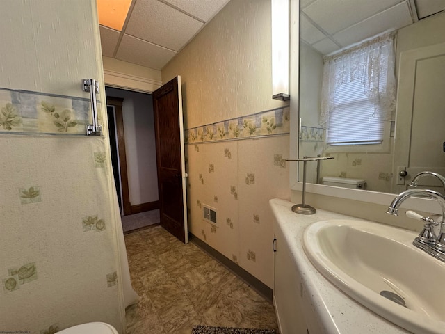 bathroom with a drop ceiling, vanity, and toilet