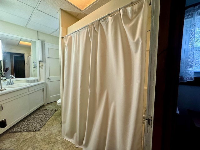 bathroom with vanity, toilet, and a drop ceiling