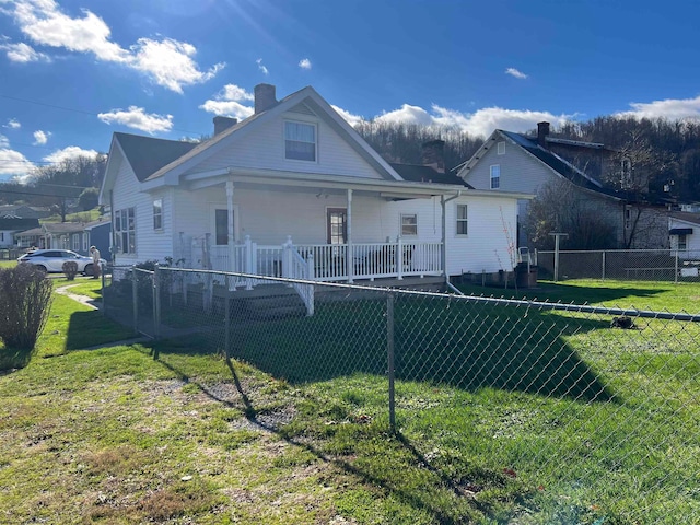 back of house with a lawn and covered porch