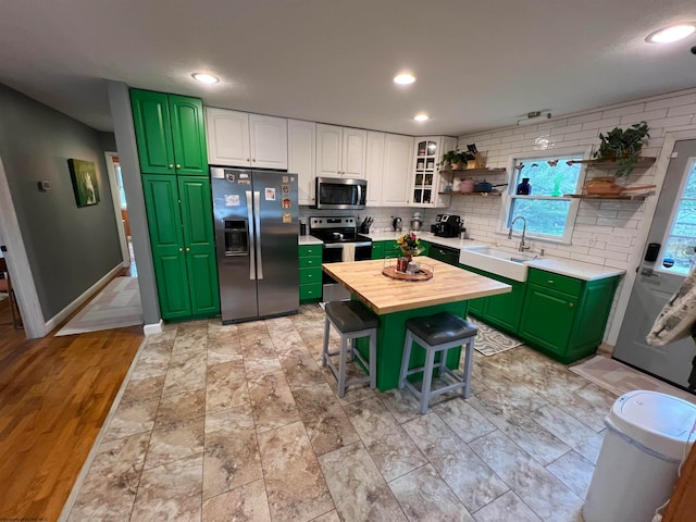 kitchen with a kitchen bar, stainless steel appliances, sink, butcher block countertops, and white cabinetry