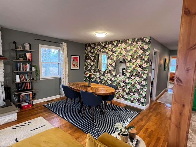 dining space with a large fireplace and hardwood / wood-style floors