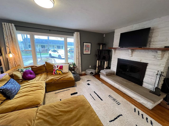 living room featuring wood-type flooring and a stone fireplace