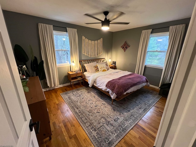 bedroom with multiple windows, dark wood-type flooring, and ceiling fan