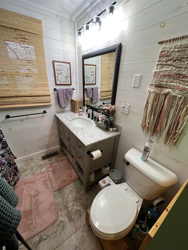 bathroom featuring tile patterned floors, vanity, toilet, and wooden walls