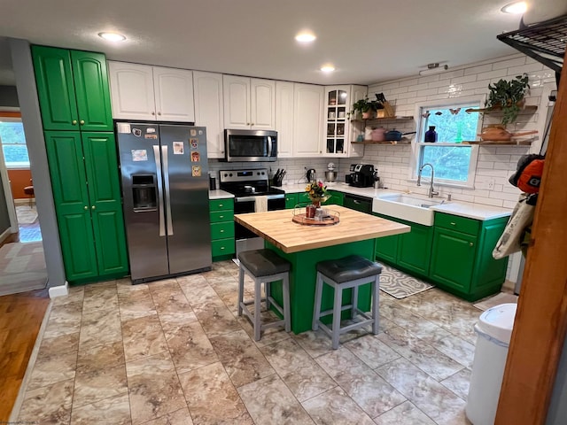 kitchen featuring butcher block counters, sink, stainless steel appliances, a kitchen bar, and white cabinets