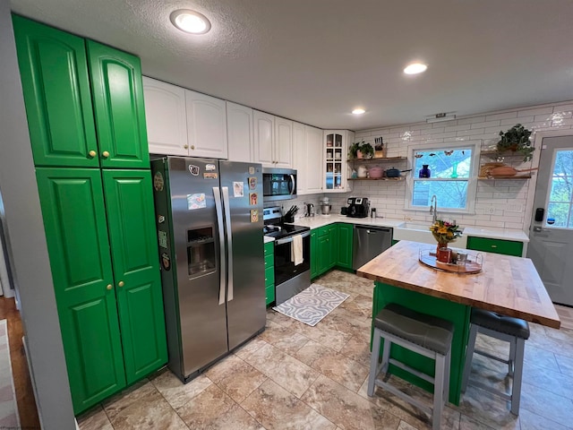 kitchen featuring backsplash, sink, white cabinetry, butcher block counters, and stainless steel appliances