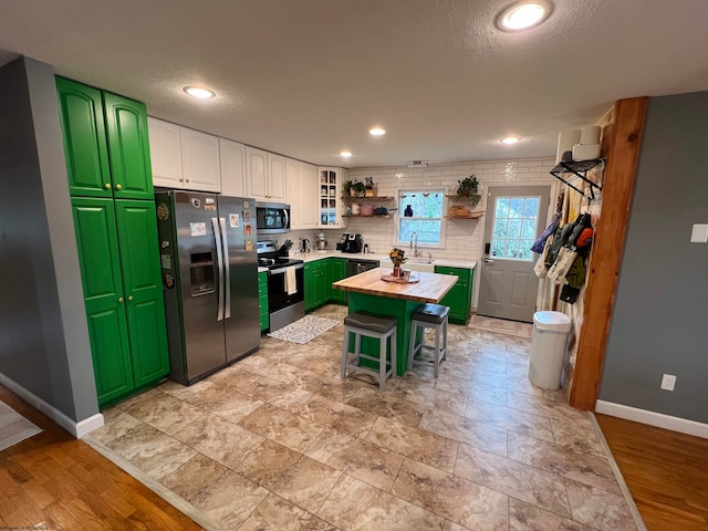 kitchen with white cabinetry, sink, stainless steel appliances, wood counters, and a kitchen island