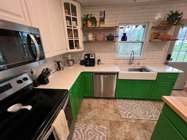 kitchen with backsplash, stainless steel appliances, sink, white cabinets, and green cabinets