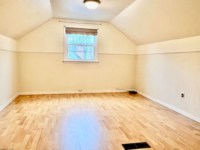 additional living space with wood-type flooring and vaulted ceiling