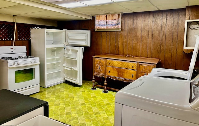 clothes washing area with washer and clothes dryer and wood walls