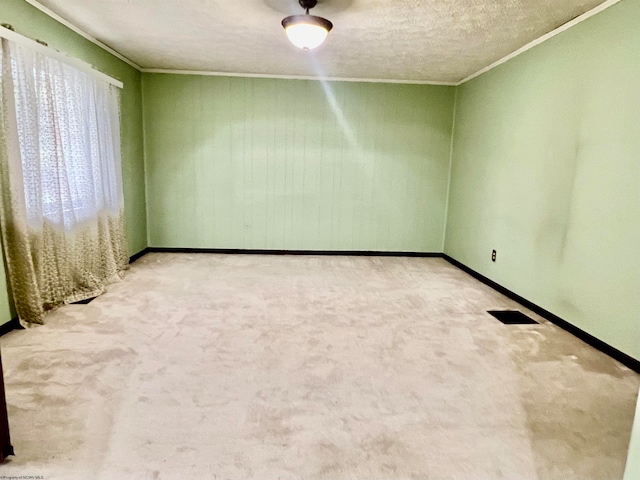 carpeted empty room with a textured ceiling and crown molding