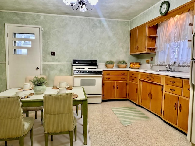 kitchen with sink, plenty of natural light, white range, and a notable chandelier