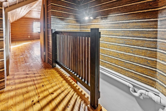 corridor with wood walls and lofted ceiling