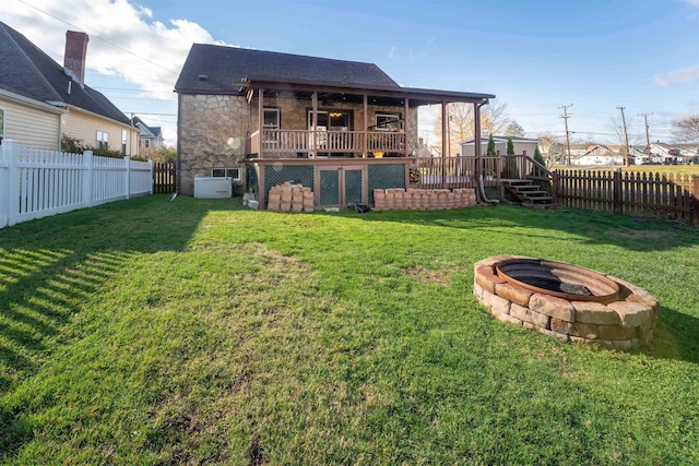 back of house featuring a lawn, a fire pit, and a deck