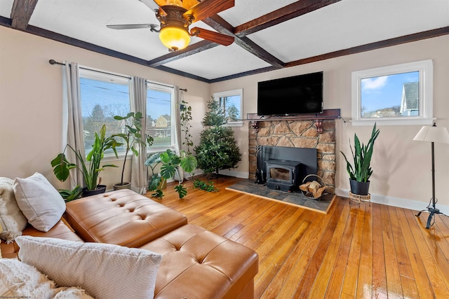 living room with beam ceiling, a wood stove, ceiling fan, and hardwood / wood-style flooring