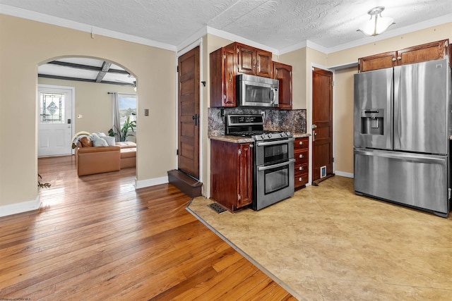 kitchen featuring appliances with stainless steel finishes, tasteful backsplash, ornamental molding, coffered ceiling, and light hardwood / wood-style floors