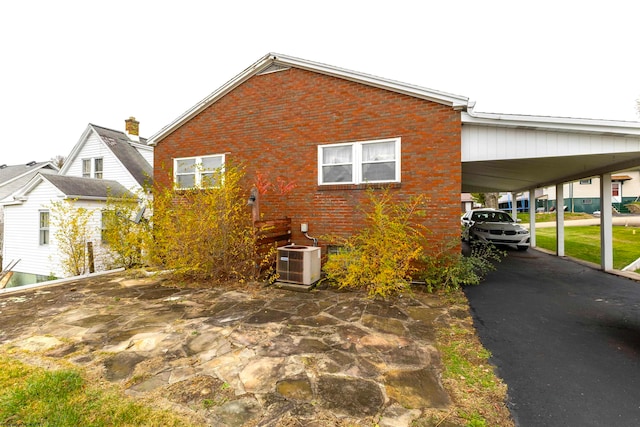 view of side of home with central AC unit and a carport