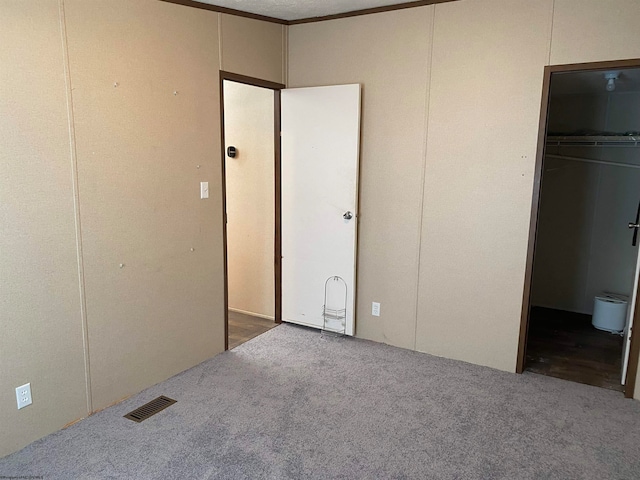 unfurnished bedroom featuring a closet, a spacious closet, and carpet