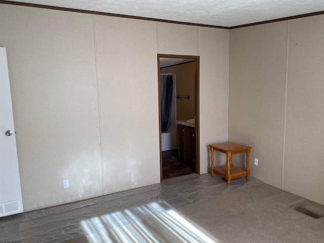 empty room with ornamental molding and a textured ceiling