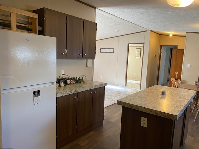 kitchen with a center island, dark hardwood / wood-style floors, a textured ceiling, white fridge, and dark brown cabinetry