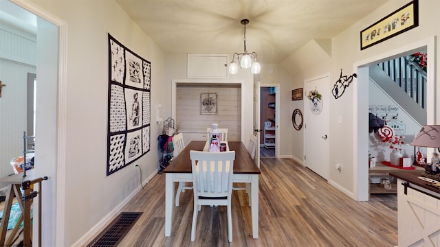 dining area with lofted ceiling, wood-type flooring, and an inviting chandelier