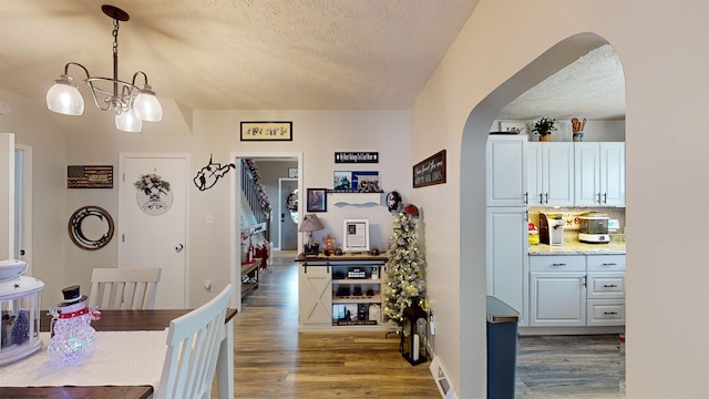 kitchen featuring dark hardwood / wood-style floors, a textured ceiling, decorative light fixtures, white cabinetry, and a chandelier