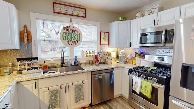 kitchen featuring white cabinetry, sink, stainless steel appliances, light hardwood / wood-style flooring, and a textured ceiling