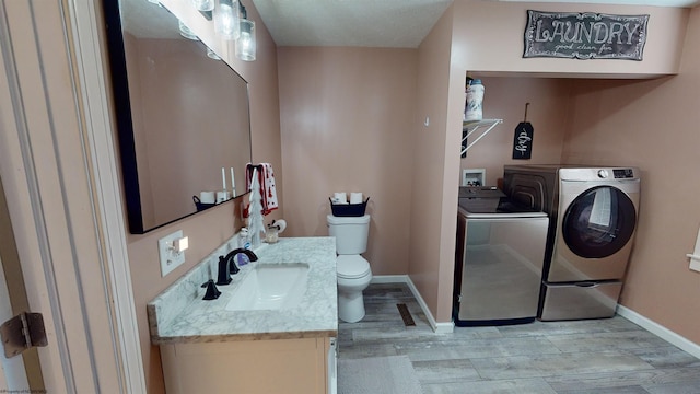 bathroom with separate washer and dryer, hardwood / wood-style flooring, vanity, and toilet