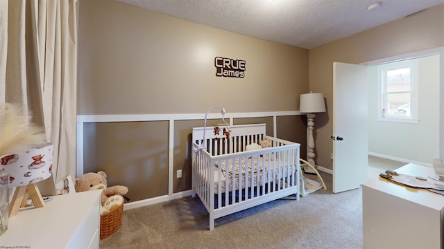 bedroom with carpet flooring, a nursery area, and a textured ceiling