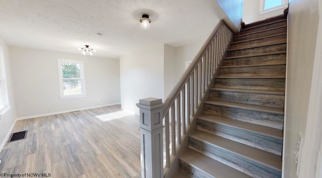 staircase with hardwood / wood-style floors and a textured ceiling