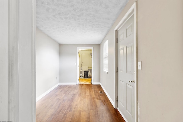 hall with a textured ceiling and hardwood / wood-style flooring