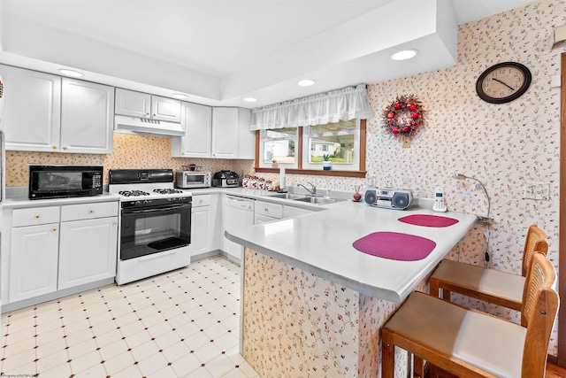 kitchen featuring kitchen peninsula, a kitchen breakfast bar, white appliances, and white cabinets