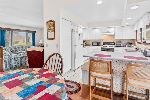 kitchen featuring white cabinetry, sink, tasteful backsplash, light hardwood / wood-style flooring, and black appliances