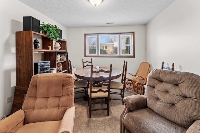 carpeted dining room with a textured ceiling