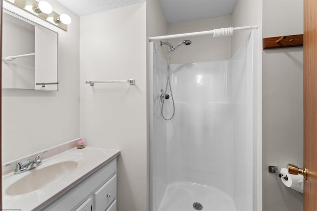 bathroom with a shower, vanity, and a textured ceiling