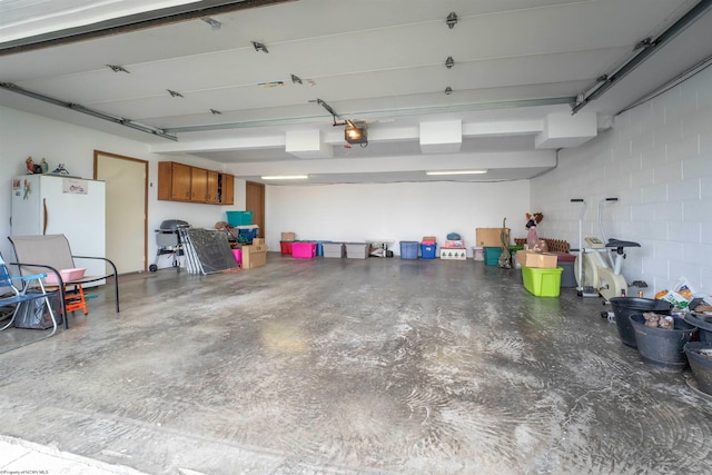 garage featuring white fridge and a garage door opener