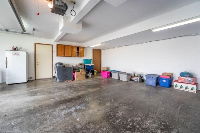 garage featuring white refrigerator and a garage door opener