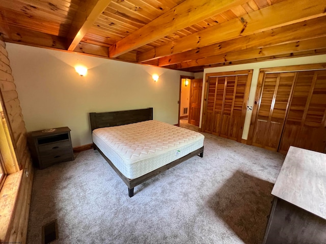 bedroom with beamed ceiling, carpet floors, wood ceiling, and two closets