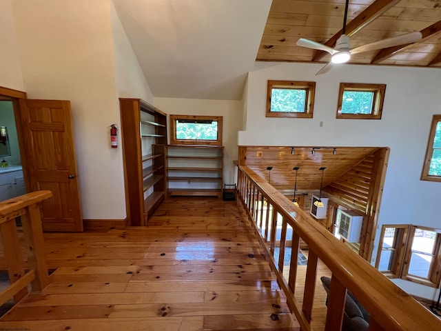 hall with beam ceiling, light hardwood / wood-style flooring, high vaulted ceiling, and wood ceiling