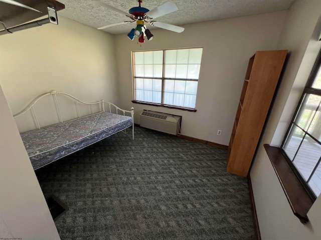 unfurnished bedroom featuring ceiling fan, a textured ceiling, a wall unit AC, and multiple windows